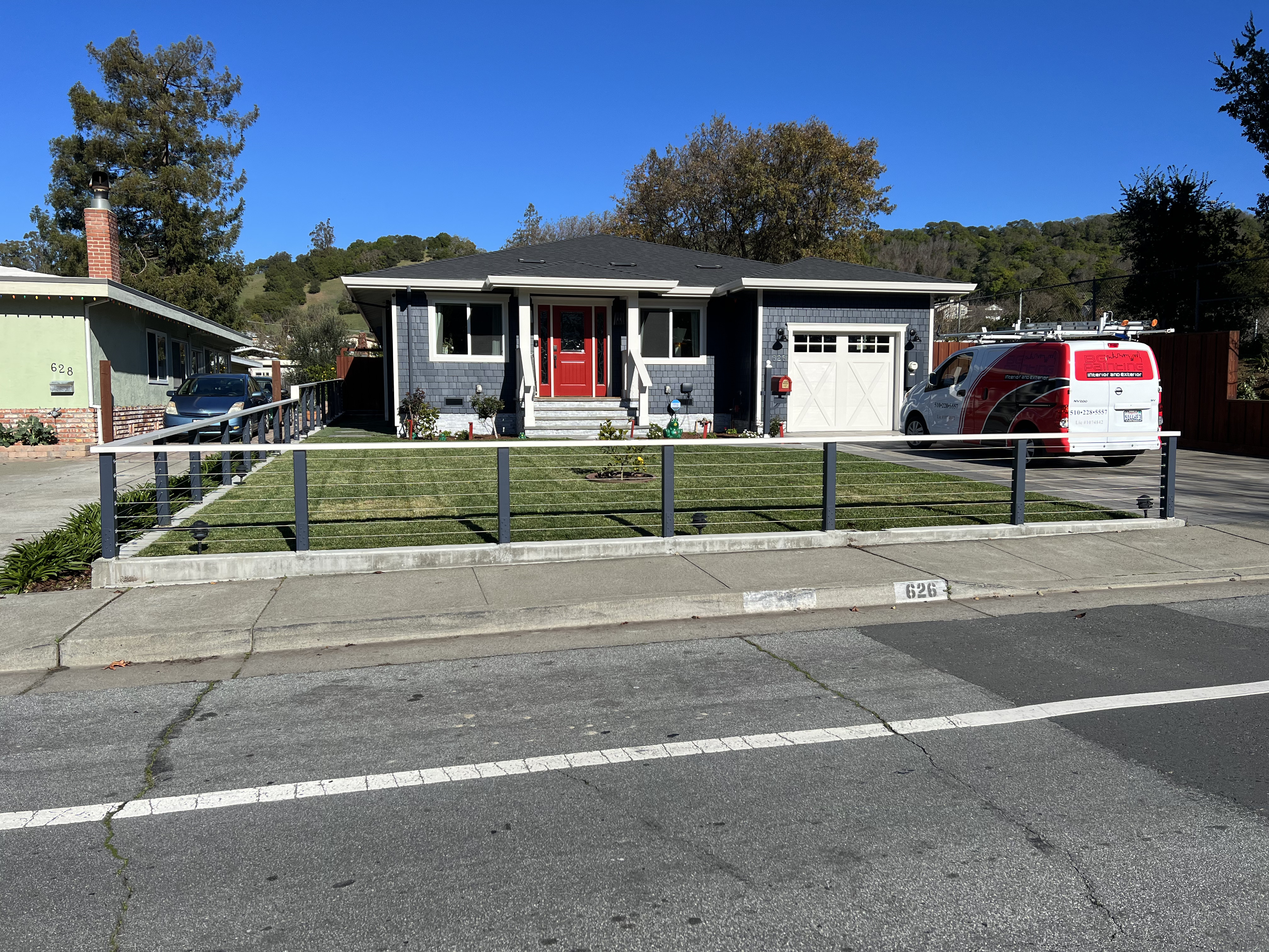 Front view of navy blue craftsman home with red door